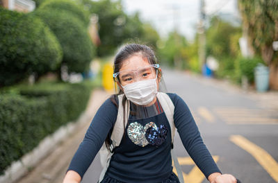 Mother puts a safety mask on daughter face for protection covid-19 outbreak to prepare go to school.