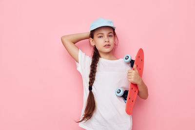 Portrait of cute girl holding gift against pink background