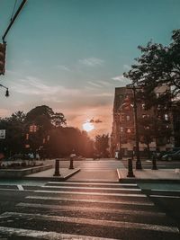 Road by city against sky during sunset