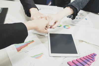 Colleagues clenching fists over table in office