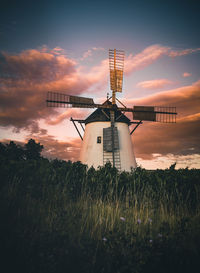 Traditional windmill on field against sky during sunset