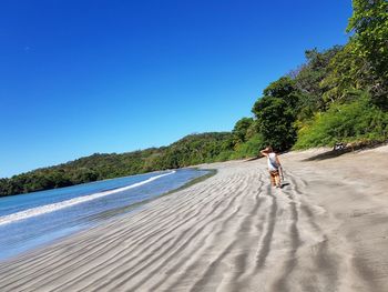 Man on shore against clear blue sky