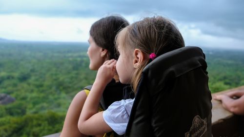 Rear view of mother and daughter against sky