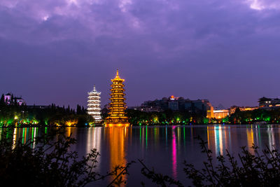 Canal amidst illuminated buildings in city at night