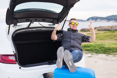 Full length portrait of young man in car