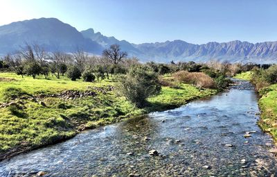 Scenic view of river by mountains against sky