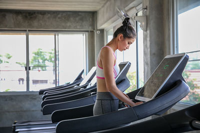 Side view of woman standing on treadmill at gym