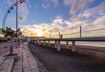 Bridge over street against sky during sunset