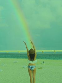 Rear view of woman standing at beach against sky