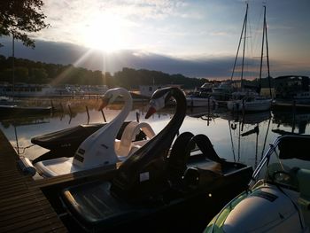 Boats moored in harbor at sunset
