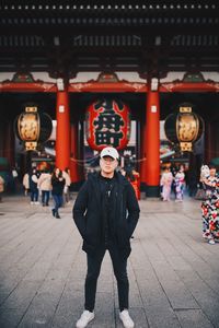 Portrait of young man standing against building
