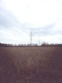 Electricity pylon on field against sky