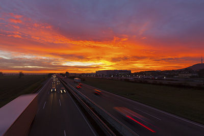 Light trails on road against sky at sunset