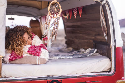 Young woman sleeping on bed in caravan