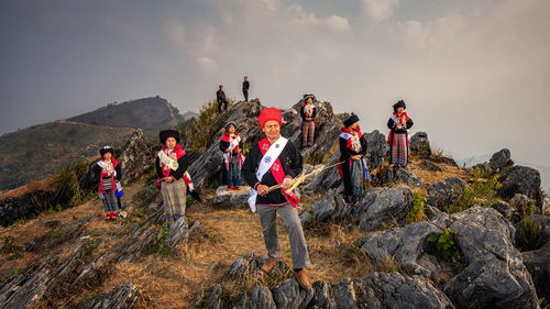 People on rock against sky