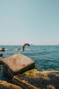 Full length of teenage boy diving in sea against sky
