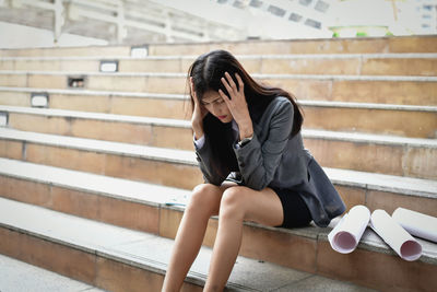 Stressed businesswoman with head in hands sitting on steps