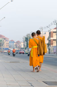 Rear view of people walking on street in city