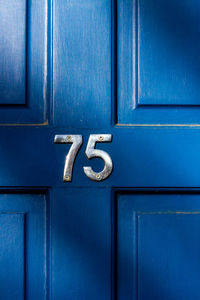 House number 75 on a blue wooden front door in london 