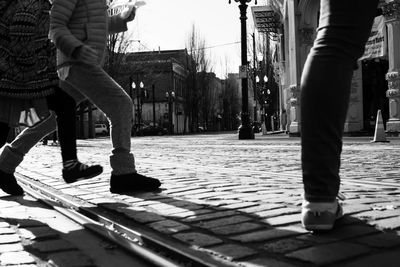 Low section of women walking on sidewalk in city