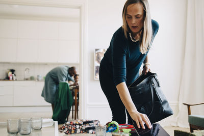 Mid adult woman putting digital tablet in bag at home