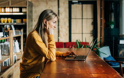 Young woman using mobile phone while sitting on table