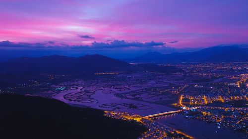 High angle view of illuminated town against sky at night