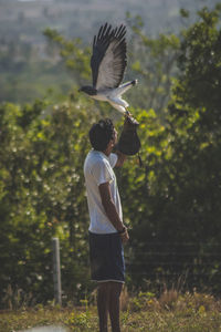 Side view of man holding bird outdoors