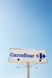 Low angle view of road sign against clear blue sky