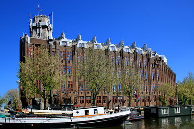 Boats in canal against clear blue sky