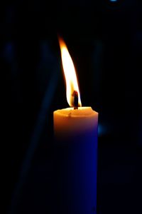 Close-up of burning candle against black background