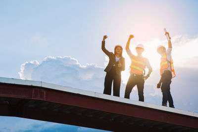 Low angle view of people standing against sky