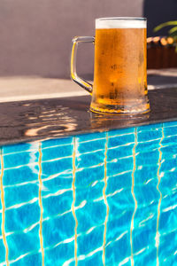 Glass of water on table by swimming pool