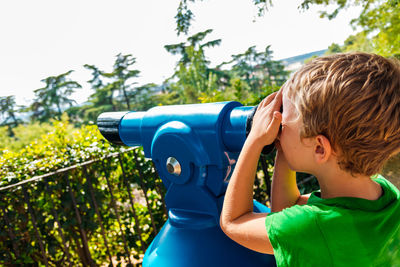 Side view of boy looking through binoculars 