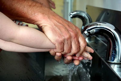 Midsection of man with hands in water at home