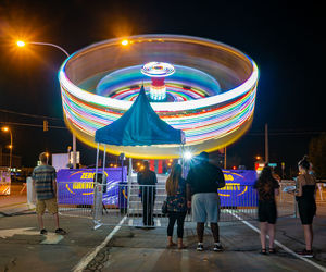 People at illuminated stage against sky in city at night