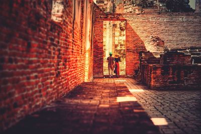 Rear view of man walking on alley amidst buildings