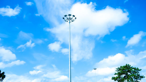 Low angle view of electric poles against blue sky