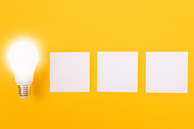 Close-up of illuminated light bulb against yellow wall