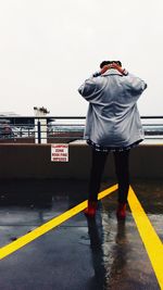 Rear view of man standing on mobile phone against sky