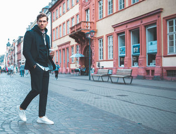 Full length portrait of young man standing on street in city