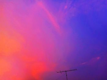 Low angle view of silhouette communications tower against sky during sunset