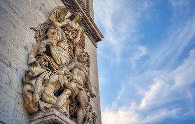 Low angle view of statue of historical building against cloudy sky