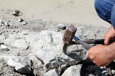 Cropped image of hands hammering on chalk rocks