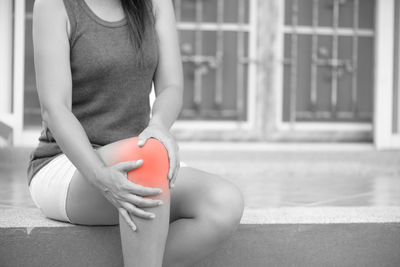 Midsection of woman suffering from pain while sitting on step