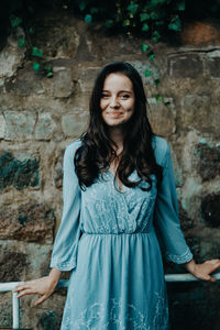 Portrait of a smiling young woman standing against wall