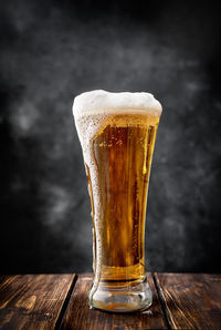 Close-up of beer glass on table against black background