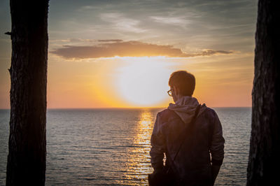 Rear view of man standing on beach during sunset