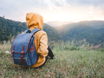 Woman hiking with backpack relaxing in nature and enjoy the sunset view on mountain peak.