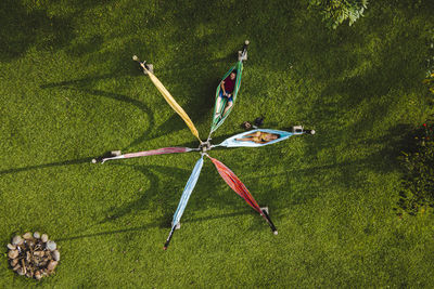 Drone top view couple in summer wear chilling on hammocks arranged in shape of star in verdant summer garden